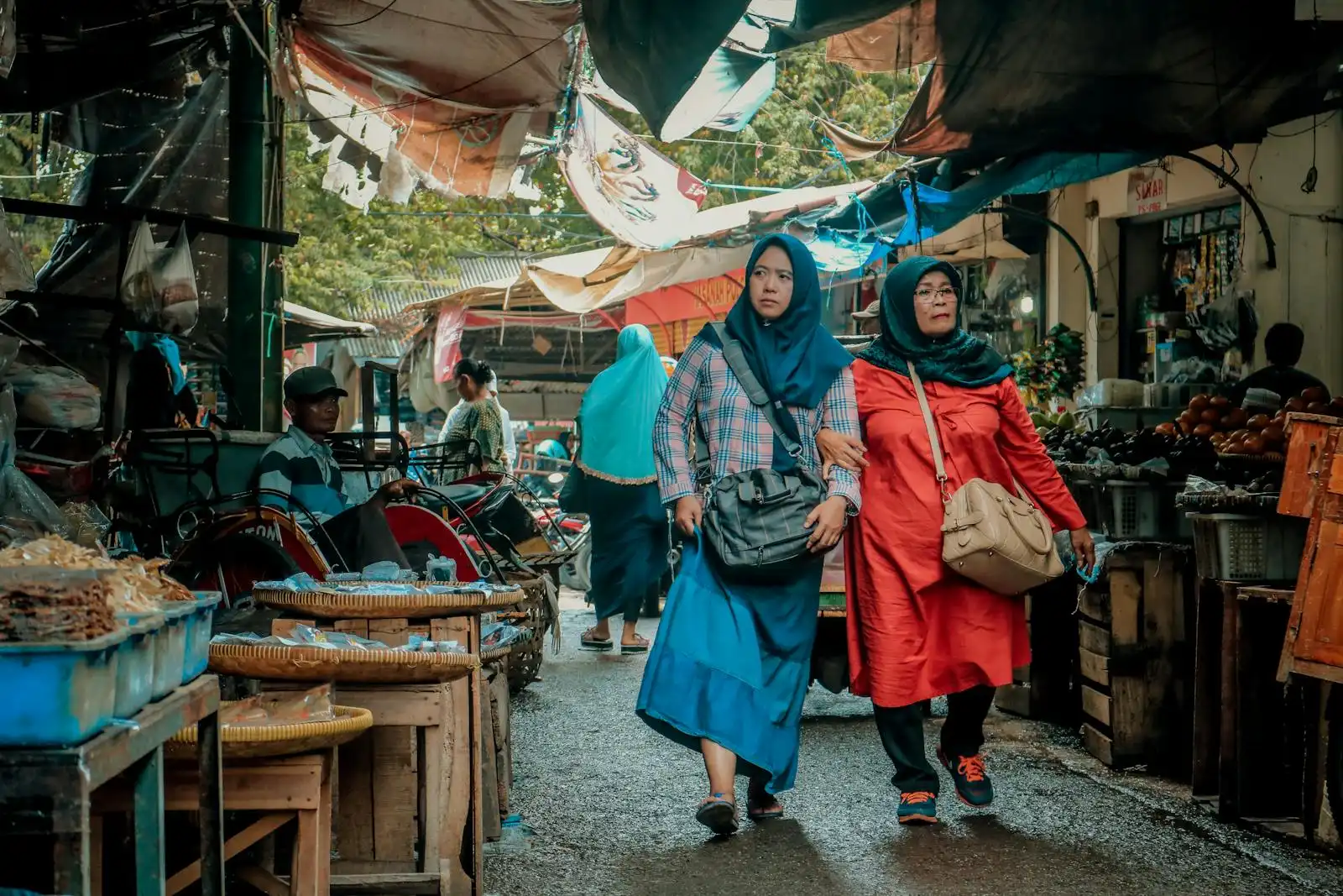 Two women shopping at a lively traditional market in Indonesia, showcasing local culture and commerce.